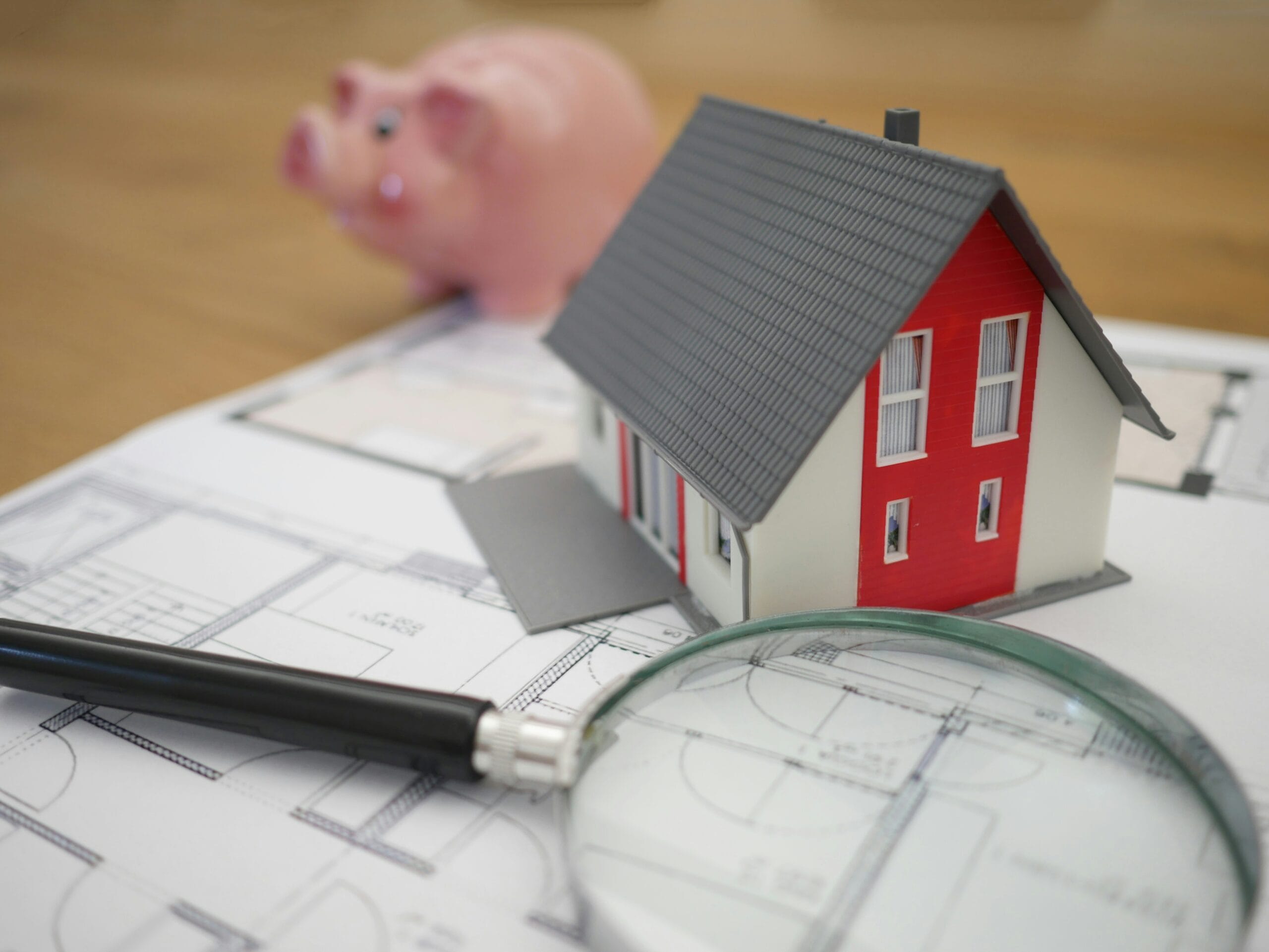 Cost of Living image of a small house with magifying glass, piggy bank and paper