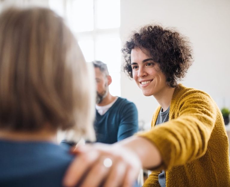 Men and women sitting in a circle during group therapy, supporting each other.