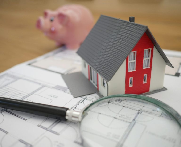 Cost of Living image of a small house with magifying glass, piggy bank and paper